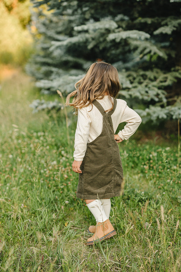 Green corduroy dress for babies, angle view showcasing soft fabric and stylish design. Perfect for any occasion.