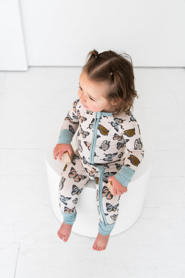 Social Butterfly Zipper Lounger for babies, cozy loungewear in playful design, shown from angle 6.