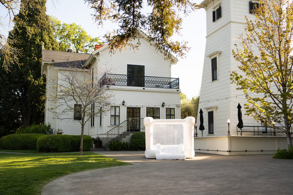 Mini Alex White Bounce House with Flat Tops for outdoor play, shown from angle 2. Perfect for kids' fun and exercise.