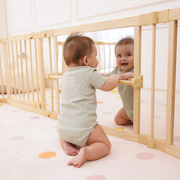Wooden baby playpen with mirror and whiteboard panel, foldable 63" x 63", Montessori sensory play yard, angle view.