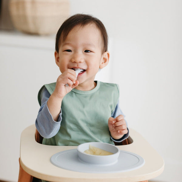 Solid Sage Minimalist Bapron for babies, shown at an angle, featuring a stylish and functional design.
