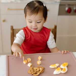 Solid candy apple red minimalist bapron for babies, angle view showcasing its stylish design and practicality.