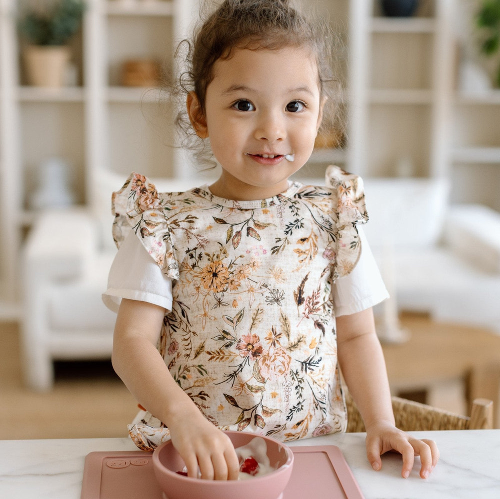 Delilah Floral Flutter Bapron for babies, featuring a vibrant floral design and flutter sleeves, perfect for mealtime.