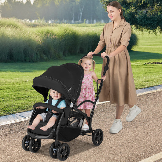 Foldable twin tandem stroller in black, featuring adjustable handlebar and sit-and-stand design, viewed from angle 2.