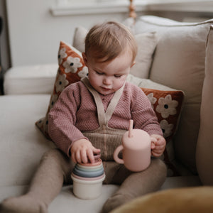 Silicone training cup with straw for babies, angled view showcasing its ergonomic design and vibrant colors.