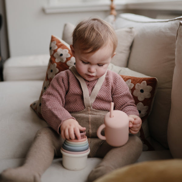 Silicone training cup with straw for babies, angled view showcasing its ergonomic design and vibrant colors.