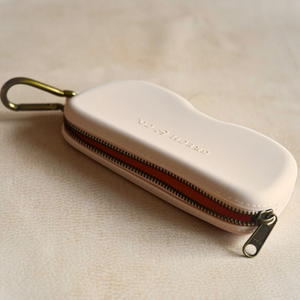 Soft silicone Zip + Go Case in sand color, perfect for baby accessories and seasonal wear. Angle 2 view.