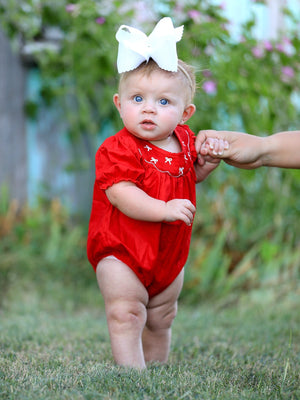 Girls red romper with bow smocking and embroidery, shown from angle 2. Perfect for stylish baby outfits.