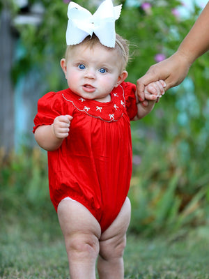 Girls red romper with bow smocking and embroidery, shown from angle 3. Perfect for stylish baby outfits.