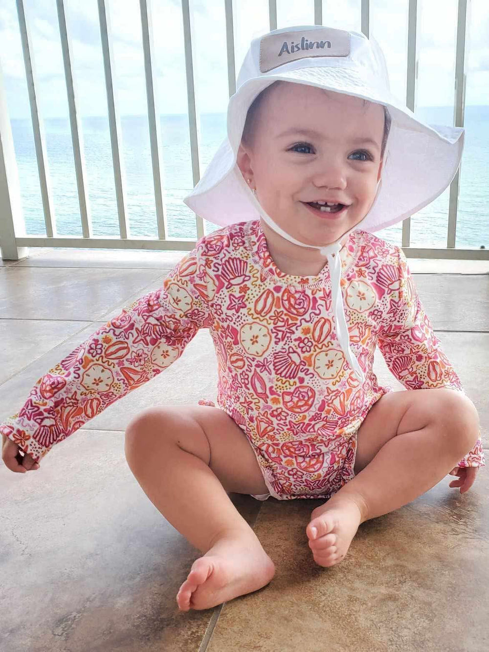 Pink seashell rash guard swimsuit for babies, perfect for sun protection and fun in the water.