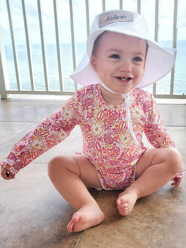 Pink seashell rash guard swimsuit for babies, perfect for sunny beach days and water play. Angle 2 view.