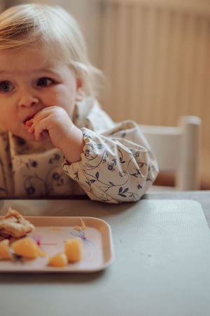 Scandi floral smock bib for babies, angled view showcasing vibrant design and practical features.