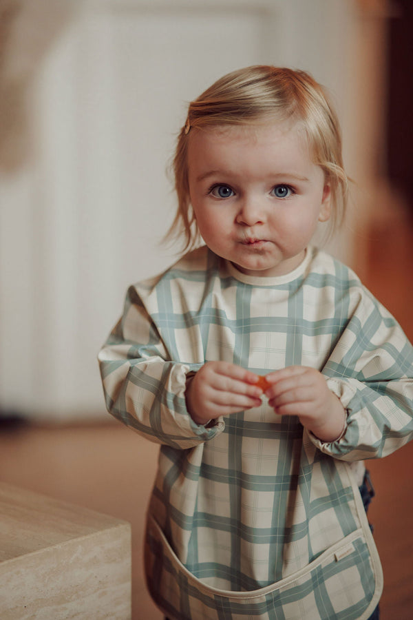 Fern plaid smock bib for babies, angle view showcasing stylish and practical design for mealtime messes.