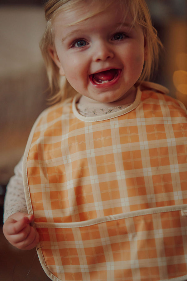 Basic Bib in Buckwheat Plaid, angle view showcasing stylish and functional baby feeding accessory.