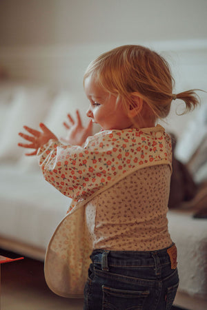 Smock Bib in Sunset Meadow design, angle view showcasing vibrant colors and practical features for messy mealtimes.
