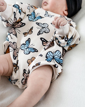 Baby bubble romper with butterfly print, angled view showcasing vibrant colors and playful design. Perfect for little ones!
