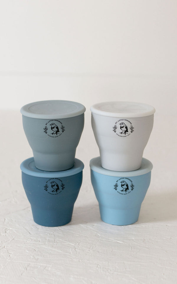 Collapsible silicone snack cups in various colors, perfect for toddlers and on-the-go snacks. Angle view.