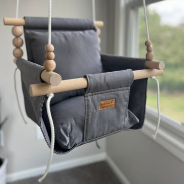 Gray indoor baby swing for comfortable and safe playtime.