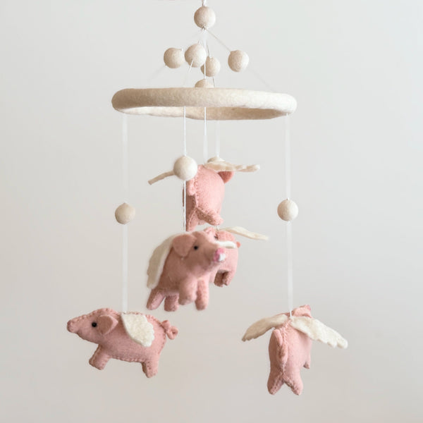 Front view of the felt flying pig baby mobile, wool felt pigs suspended from a cream felt hoop with pom poms.