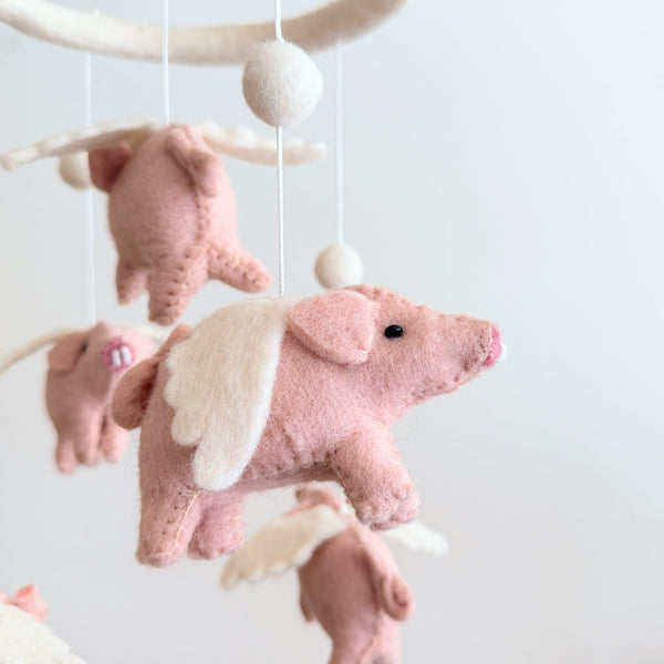 Close-up of one flying pig felt figure showing hand-stitched wings, black eyes, and pink nose detail.