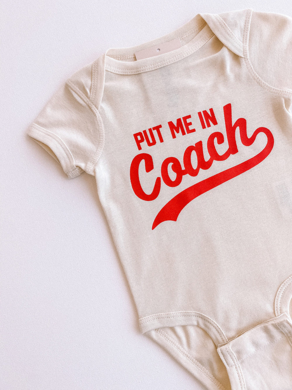 "Put Me In Coach short sleeve onesie for babies, perfect for playful and sporty outfits."