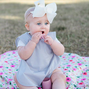 Light gray minimalist bapron for babies, angled view showcasing its stylish design and practical features.