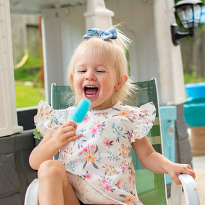 Pastel Floral Flutter Bapron for babies, angled view showcasing vibrant floral design and flutter sleeves.