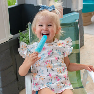 Pastel Floral Flutter Bapron for babies, angled view showcasing vibrant floral design and flutter sleeves.