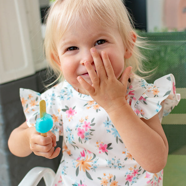 Pastel Floral Flutter Bapron for babies, angled view showcasing vibrant floral design and flutter sleeves.