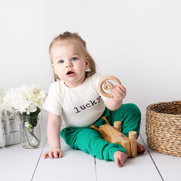 Graphic bodysuit for babies in 'Lucky' design, short sleeves, angle view showcasing vibrant colors and playful style.