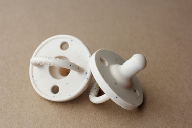 Silicone pacifier in speckled vanilla color, perfect for soothing babies comfortably and safely.