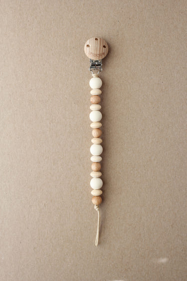 Cream Amor Pacifier Clip for babies, stylish and functional, keeps pacifiers close and clean.