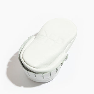 Newborn bright white moccasin baby shoe, angle view showcasing soft design and comfortable fit for infants.
