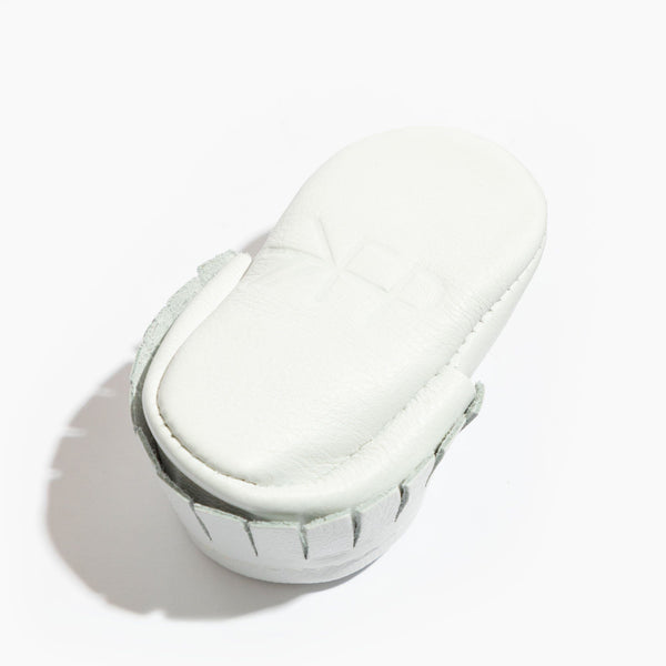 Newborn bright white moccasin baby shoe, angle view showcasing soft design and comfortable fit for infants.