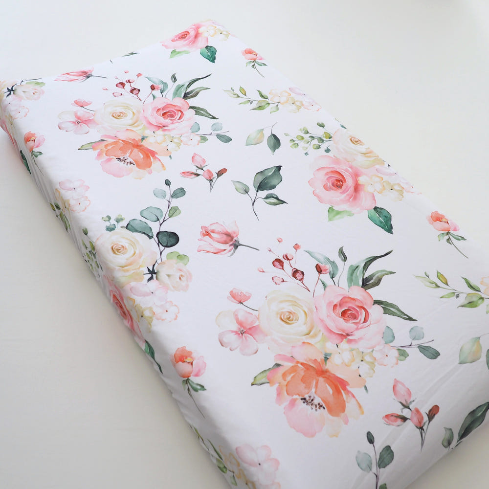 Peach floral changing pad cover for babies, perfect for nursery decor and comfort during diaper changes.