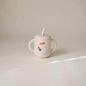 Silicone training cup with straw, angled view, perfect for toddlers learning to drink independently.