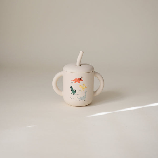 Silicone training cup with straw, angled view, perfect for toddlers learning to drink independently.