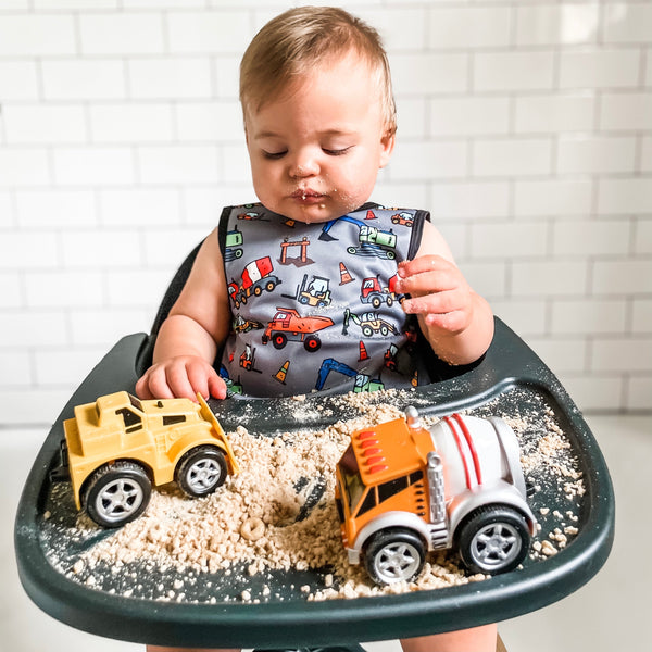 "Construction Zone Bapron for babies, featuring fun construction-themed design, angled view showcasing its playful style."