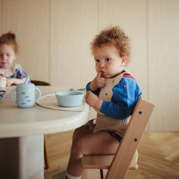 Silicone training cup with straw, angled view, perfect for toddlers learning to drink independently.