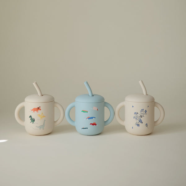 Silicone training cup with straw for babies, angled view showcasing its ergonomic design and vibrant colors.