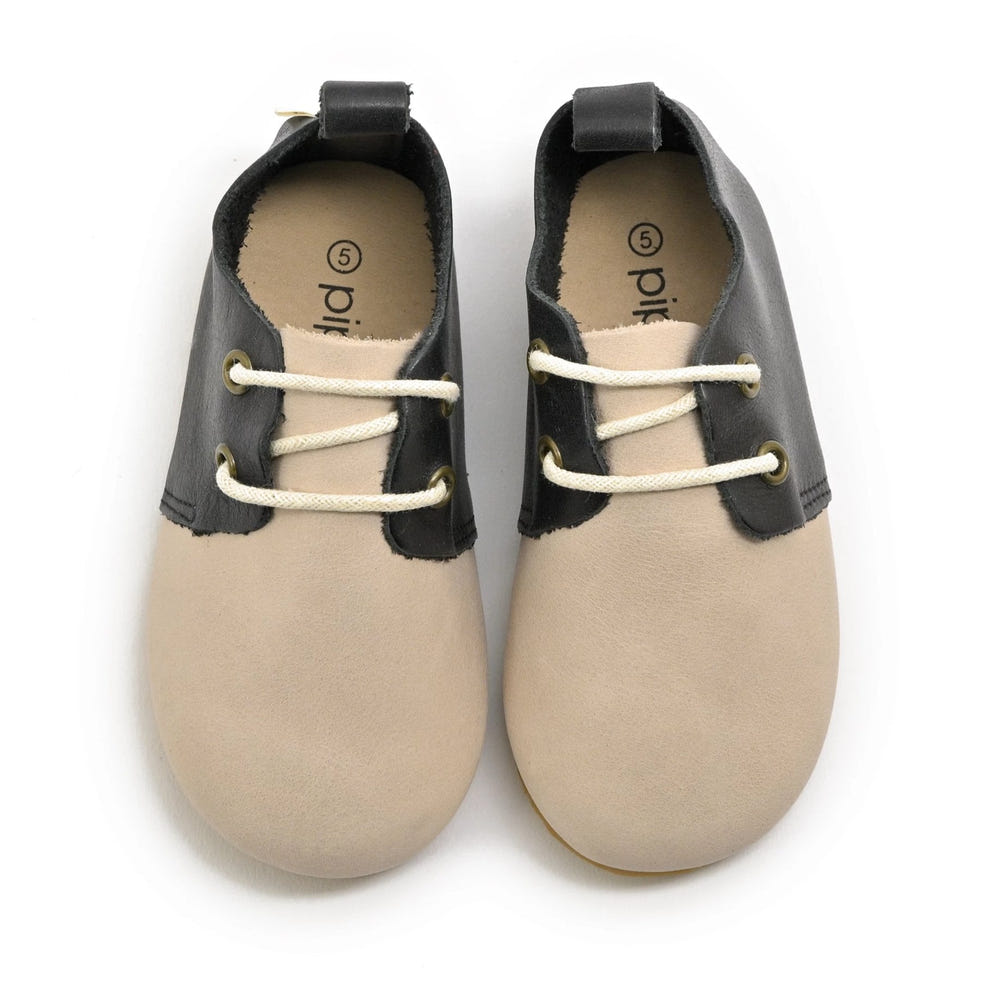 Low top baby oxfords with hard sole in stylish saddle design, perfect for little feet.