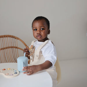 Silicone training cup with straw, angled view, perfect for toddlers learning to drink independently.