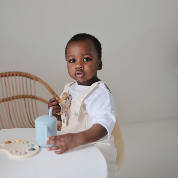 Silicone training cup with straw, angled view, perfect for toddlers learning to drink independently.