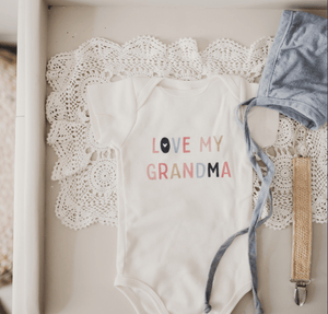 Short sleeve baby bodysuit with "Love Grandma" graphic, angle view showcasing design and fabric.