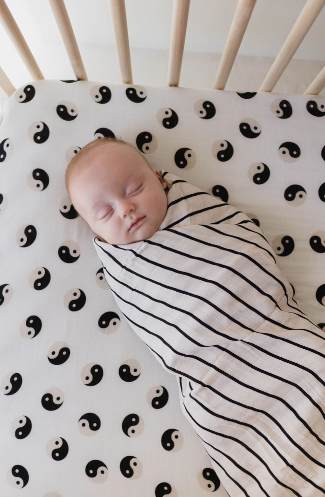 Muslin crib sheet in black and ivory yin yang design for stylish nursery bedding.