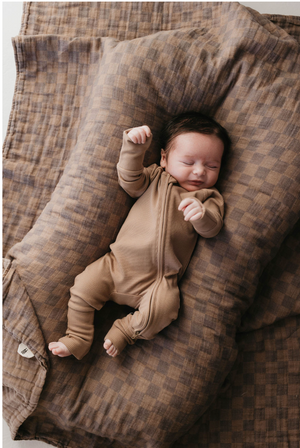 Faded brown checkerboard muslin quilt for babies, showcasing a cozy and stylish design from an angled view.