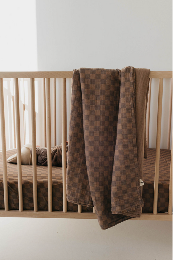 Faded brown checkerboard muslin quilt for babies, soft and stylish bedding essential.