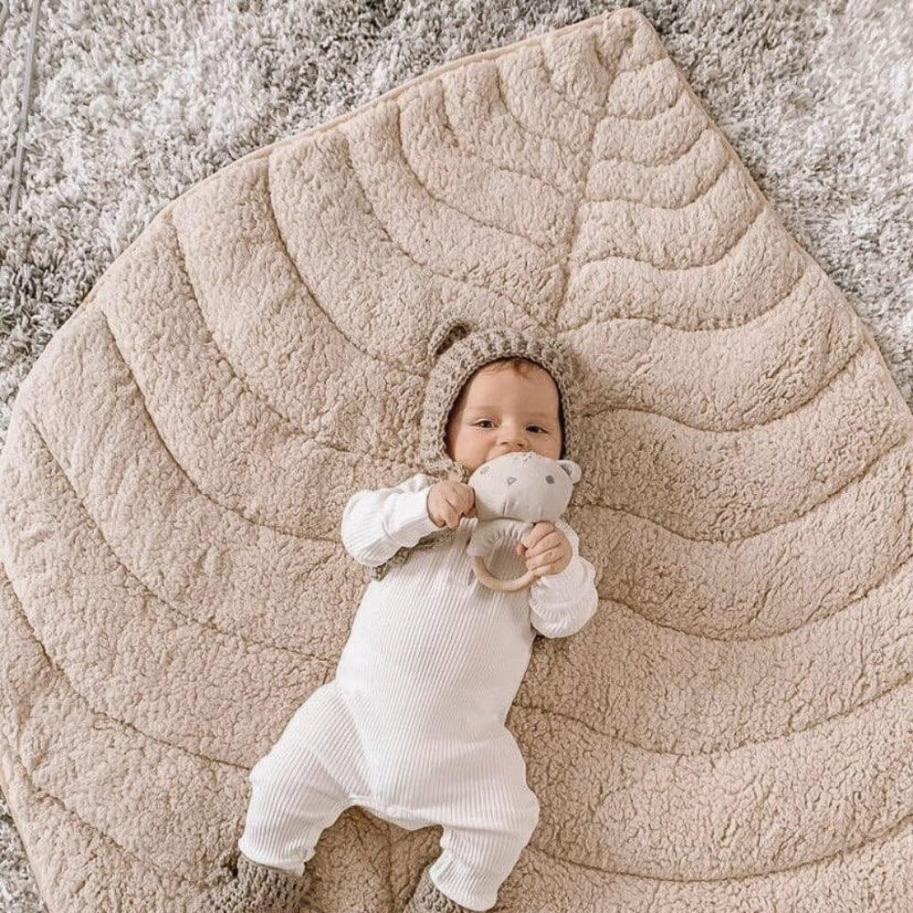 Leaf-shaped ivory sherpa and cotton baby playmat for comfortable playtime. Perfect for infants and toddlers.