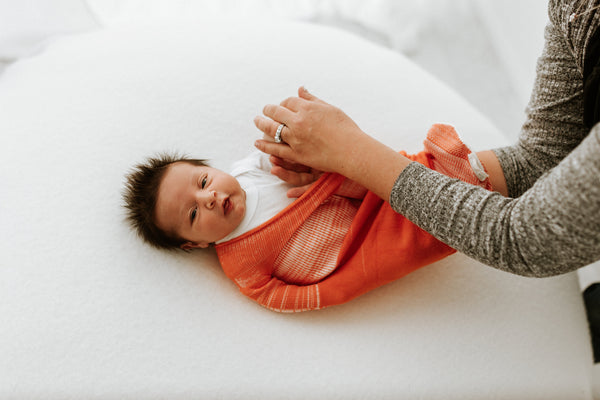 Orange Swaddle Sleep Sack from Swaddelini, shown at angle 3, perfect for keeping your baby cozy and secure.