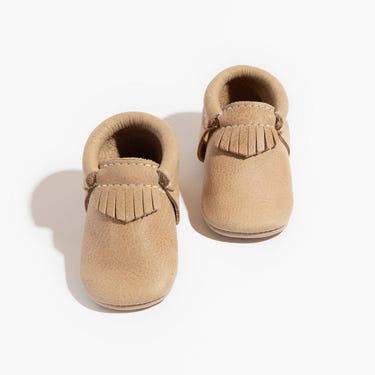 Weathered brown city baby shoe, stylish and comfortable moccasin for urban adventures.